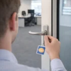 Person unlocking an office door with a Keystash Key Rings Square labeled BANDAI NAMCO.