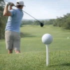 A golfer swings at a Teehint Golf Tees on a lush green course.