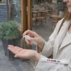 Someone uses Neatcare Hand Sanitiser Sticks outside a café.