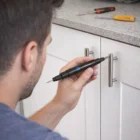 A man uses Moltz Screwdriver Sets to tighten a cabinet handle in his kitchen.