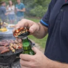 Someone opens a drink with a Rokit Magnetic Bottle Opener at a grill with friends nearby.
