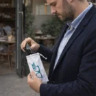 A man puts sunglasses into a white Azzera Microfibre Pouch with a blue logo.