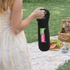 Woman holding The Davis Single Wine Cooler near a picnic blanket with food and a basket.