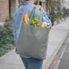 Someone carries groceries in a gray Vegas Budget Tote Bag on a Vegas sidewalk.