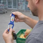 Man holding keys on a Bolt Carabiner Key Ring near a basket of fruits and vegetables.