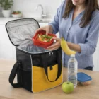 Woman packs salad, banana, apple, and water into an Otelli Cooler Bag for lunch.