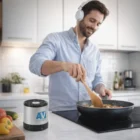 Man cooking with headphones, Audiohub Bluetooth Speakers on the kitchen counter nearby.