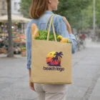 Woman carrying Kallie Jute Tote Bag with beach logo, filled with groceries, walking outdoors.