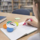 Person using an Iris Flower Highlighter at a library table near an iris blossom.