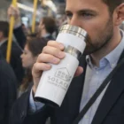 Man drinking from a Classic Decorated Travel Tumbler on a crowded train.