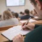 A student uses Rizal Centra Pens to take notes in a notebook during a lecture with classmates.