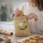 Woman puts a cookie into a Sari Jute Gift Bags Medium by a plate of cookies.