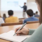 Student jotting notes in class using Workwise Pens as the teacher instructs up front.