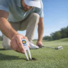 A golfer fixes a green with a Brix Golf Divot Repairer.