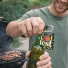 Smiling man uses Snaxi Pvc Bottle Openers by a grill at Newport Food Fest 2016.