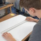Teenager using a Personalised Plastic 300Mm Ruler to draw lines on a large white sheet.