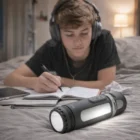 Teen boy with headphones writes on bed, Bluetooth Swiss Peak Speakers nearby.