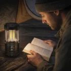 Man reading a book by Gift Camping Led Lanterns inside a tent at night.