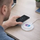 Man charging his phone with a Zoe Wireless Charger at his desk.