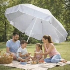 A family of four enjoys a picnic under Flamenco Beach Umbrellas in a sunny park.
