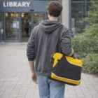 Person with a yellow and black Bagsmith Conference Satchel heads toward the library entrance.
