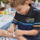 Young boy applies Temporary Tattoos Classic 38mm x 64mm at a birthday party table.
