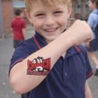 Smiling boy displays Temporary Tattoos Classic 76mm x 76mm on his forearm outdoors.
