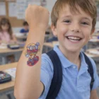 Smiling boy shows off Temporary Tattoos Foil 51mm x 51mm on his raised forearm.