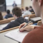 Student using Stylish Aluminium Personalised Pens in a lecture hall with peers and lecturer.