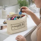 Woman holding blue nail polish next to a Rita Logo Printed Makeup Bag labeled 4HER on the counter.