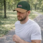 Man jogging in park, wearing a white shirt and Hylux Suede Peak Caps with graphic design.