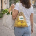 Woman carries Nalix Jute Net Bags with lettuce, bread, lemons; one labeled vegan.