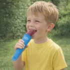 Young boy in yellow shirt enjoys a treat made with Ice Block Moulds, greenery behind him.