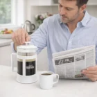 Man making coffee with The Adama Coffee Plungers while reading the newspaper at the counter.