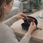 A woman puts red sunglasses into an Anvil Sunglass Case on a wooden table.