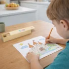 A child colors a castle drawing with Student Colouring Sets at the kitchen table.