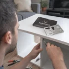 Person assembling white furniture with multitool and Kavam Multi Tool Cards in a pouch.