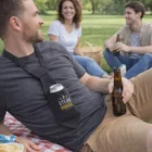 Man at picnic wears Oaken Beverage Ties, holds a beer, and chats with friends on the grass.
