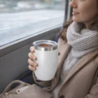 Woman in a coat and scarf holds tea in a Zesty Vacuum Cup while riding the train.