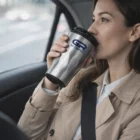Woman in a car drinks from a Bevvu Coffee Cup.
