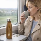A woman on a train drinks as Wiska Vacuum Bottles sit on the table.