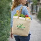 Woman carrying Cotton Jute Combo Shopper Bag with groceries and VENDE logo, walking outdoors.