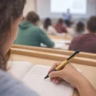 Student taking notes with Soft Grip Logo Branded Bamboo Pens during a classroom lecture.
