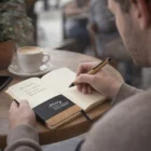 Writing in a Zilver Notebooks With Pens at a café table, coffee nearby.