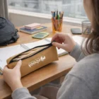Person opening a Tyvek Pencil Case at a desk with notebooks, pens, and a calculator.