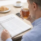 Man sipping tea from Ofolia Glass Sets 310Ml while reading newspaper and eating croissant.
