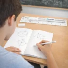 A student draws shapes in a notebook with Lora Stationery Sets on the desk.