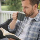 Man enjoys a book on the porch sipping from an Euka Enamel Mug.