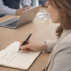 Woman writes notes with Swiss Peak Heritage Pen Set at a meeting, laptop nearby.