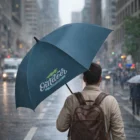 A person with a blue Verra Umbrellas and backpack walks on a rainy city street.